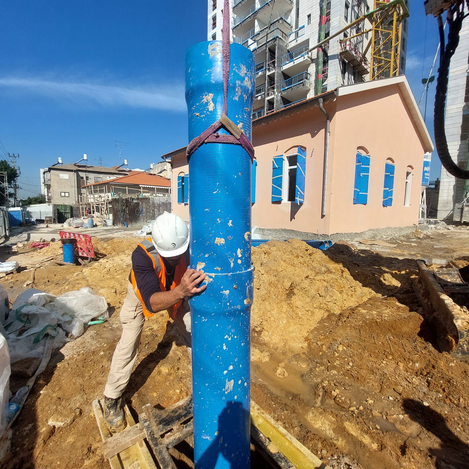 עובד בניין מתקין צינור תשתית כחול גדול באתר