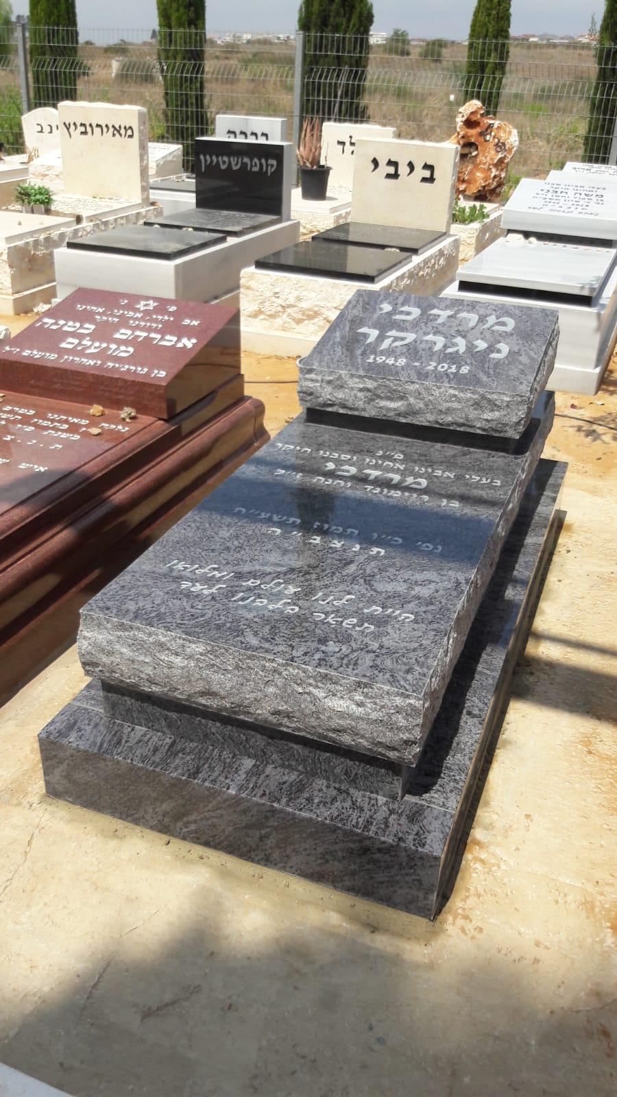 תקריב של מצבה מדורגת מגרניט אפור בבית עלמין