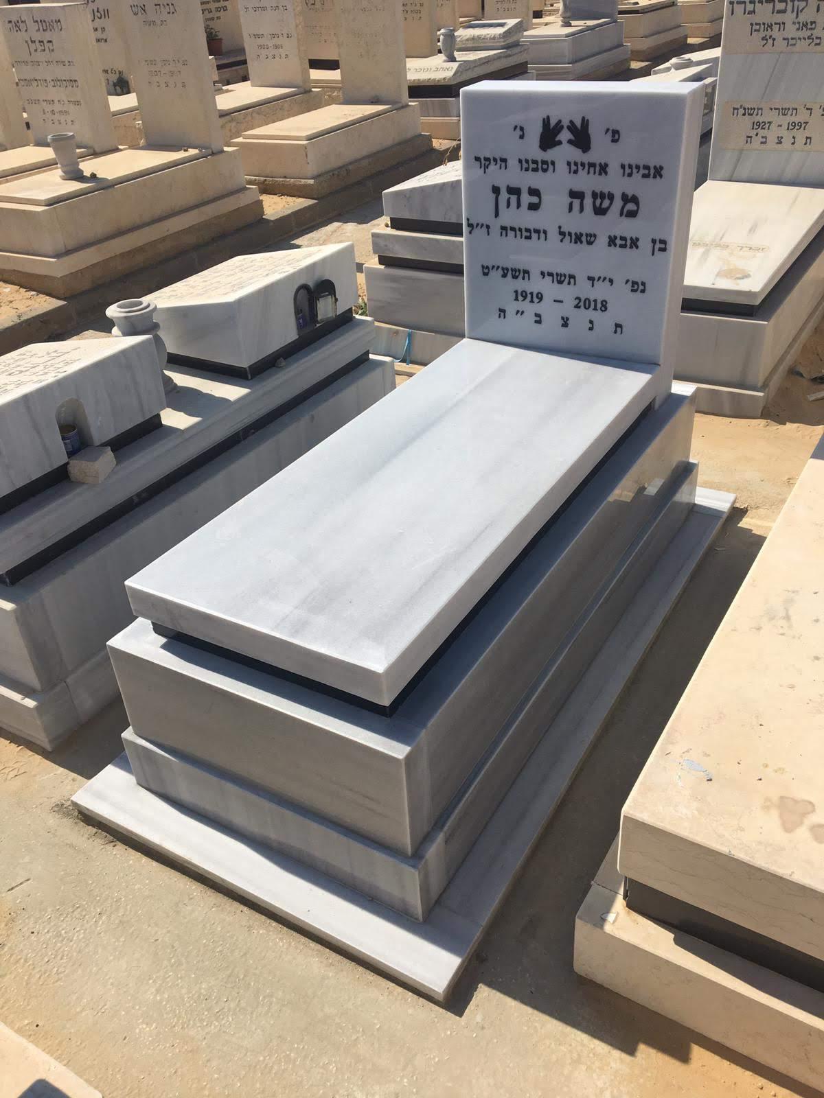 מצבת שיש לבן מדורגת עם כיתוב בחצר תצוגה