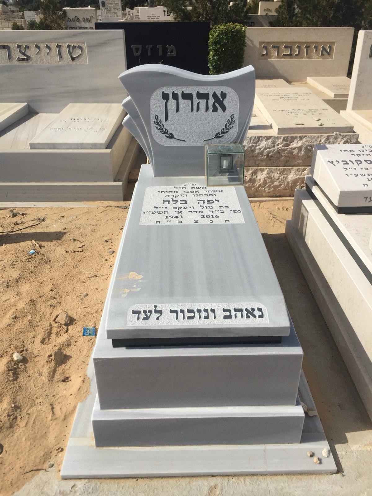 מצבה אפורה מעוצבת בבית עלמין עם כיתוב